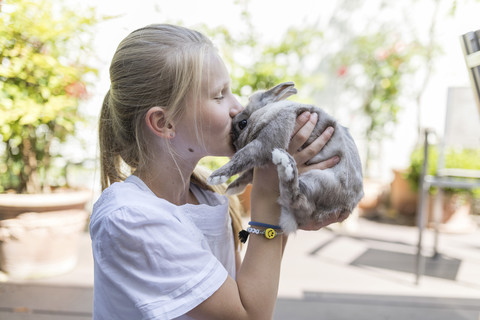 Mädchen küsst Kaninchen im Freien, lizenzfreies Stockfoto