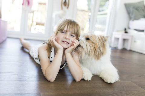 Mädchen mit Hund liegt zu Hause auf dem Boden, lizenzfreies Stockfoto