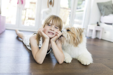 Mädchen mit Hund liegt zu Hause auf dem Boden - SHKF00790