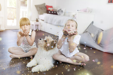 Two sisters with dog at home blowing confetti - SHKF00793