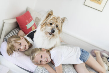 Two sisters cuddling with dog in bed - SHKF00794