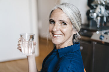 Porträt einer lächelnden Geschäftsfrau, die ein Glas Wasser hält - KNSF01773