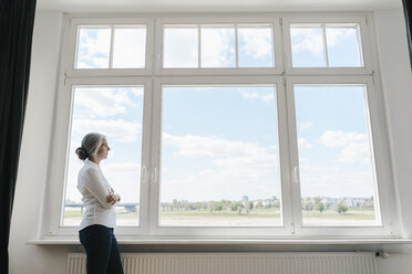 Businesswoman in office looking out of window - KNSF01780