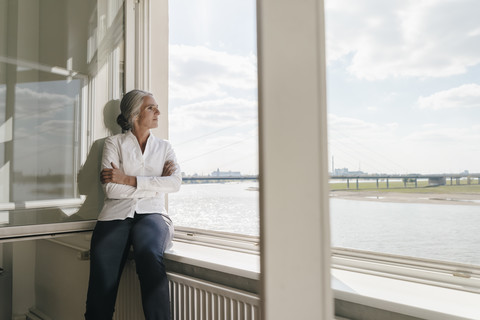 Geschäftsfrau im Büro schaut aus dem Fenster, lizenzfreies Stockfoto