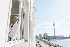 Geschäftsfrau schaut aus dem Fenster in einem Büro am Wasser - KNSF01790