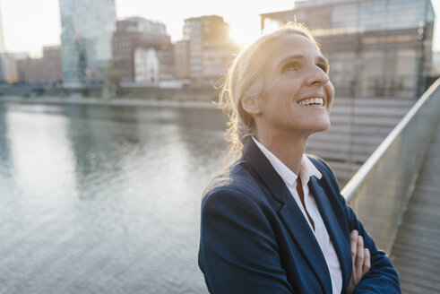 Lächelnde Geschäftsfrau auf Brücke mit Blick nach oben - KNSF01797