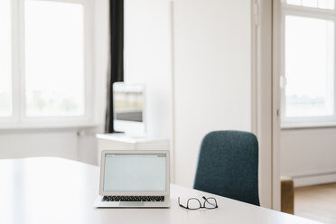 Laptop und Brille auf dem Tisch im Büro - KNSF01800