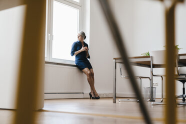 Businesswoman sitting on windiwsill - KNSF01814