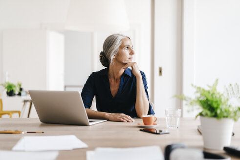 Businesswoman working on laptop in office - KNSF01821