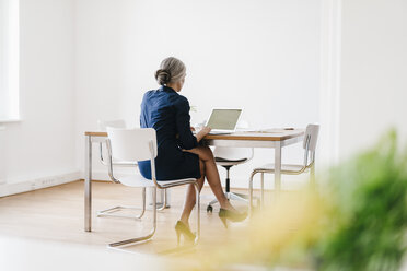 Businesswoman working on laptop in office - KNSF01822