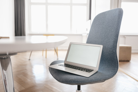 Laptop auf einem Stuhl im Büro, lizenzfreies Stockfoto