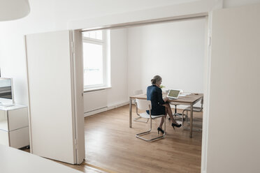 Businesswoman working on laptop in office - KNSF01853