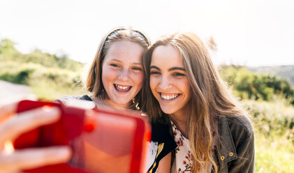 Zwei glückliche Mädchen machen ein Selfie im Freien - MGOF03428