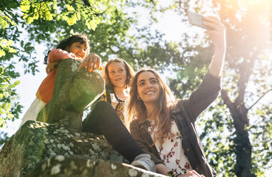 Drei glückliche Mädchen machen ein Selfie im Freien - MGOF03432