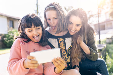 Drei verspielte Mädchen machen ein Selfie im Freien - MGOF03438