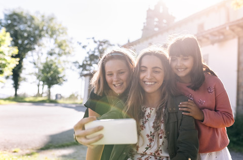 Drei glückliche Mädchen machen ein Selfie im Freien, lizenzfreies Stockfoto