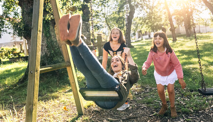 Drei glückliche Mädchen auf einem Spielplatz - MGOF03444