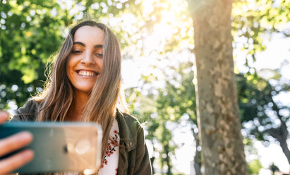 Happy young woman with smartphone putdoors - MGOF03448