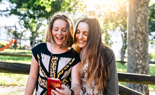 Zwei Mädchen haben Spaß mit ihrem Smartphone im Freien - MGOF03449