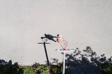 Mann spielt Basketball auf einem Platz im Freien - MAEF12340