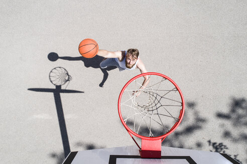 Mann spielt Basketball auf einem Platz im Freien - MAEF12342