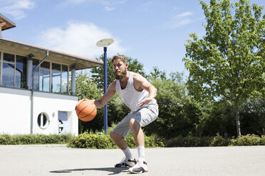 Mann spielt Basketball auf einem Platz im Freien - MAEF12343