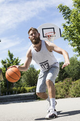 Mann spielt Basketball auf einem Platz im Freien - MAEF12344