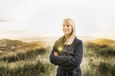 Smiling woman standing in dunes - FMKF04200