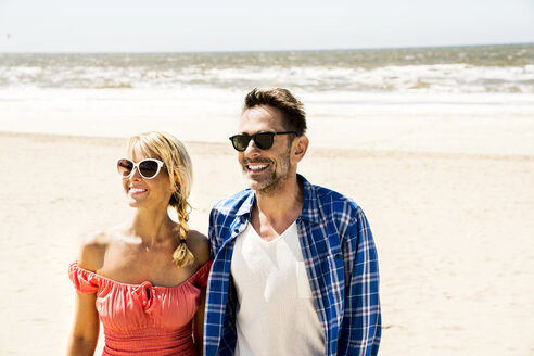 Glückliches Paar mit Sonnenbrille am Strand - FMKF04236