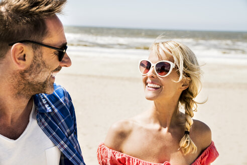 Glückliches Paar mit Sonnenbrille am Strand - FMKF04237
