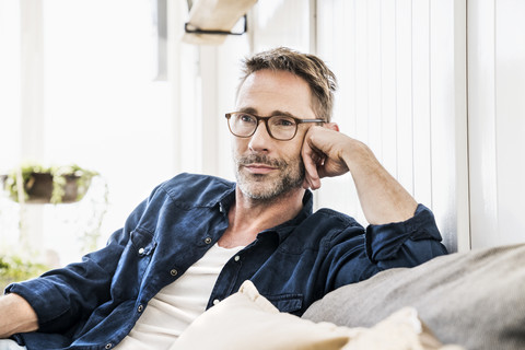 Man wearing glasses relaxing on couch stock photo