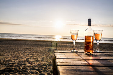 Weinflasche und Gläser auf der Promenade am Strand bei Sonnenuntergang - FMKF04243