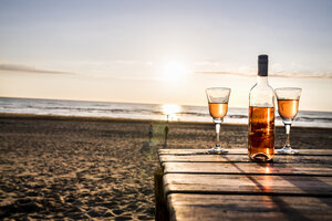 Weinflasche und Gläser auf der Promenade am Strand bei Sonnenuntergang - FMKF04243