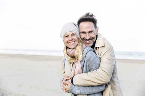 Portrait of happy couple hugging on beach stock photo