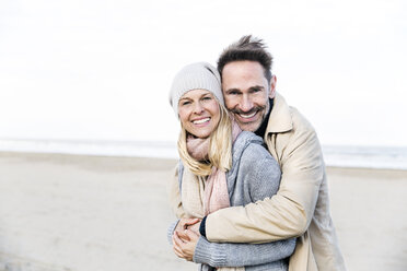 Porträt eines glücklichen Paares, das sich am Strand umarmt - FMKF04272