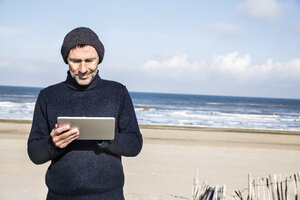 Mann benutzt Tablet am Strand - FMKF04282