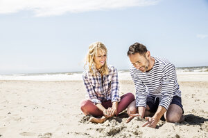 Glückliches Paar am Strand sitzend - FMKF04300