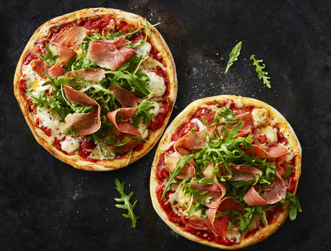 Pizza with ham and rocket on dark ground stock photo