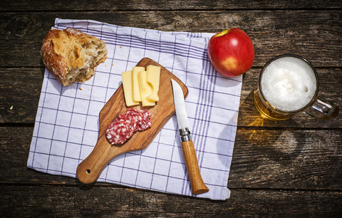 Snack mit Brot, Käse, Salami, Apfel und einem Glas Bier, lizenzfreies Stockfoto