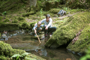 Mother and little son crouching at edge of a brook - DIKF00268