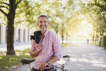 Portrait of smiling man with bicycle in a park - DIGF02576