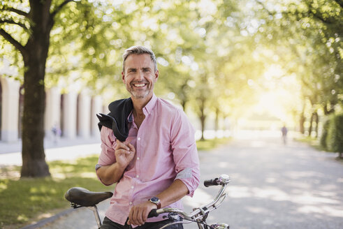 Porträt eines lächelnden Mannes mit Fahrrad in einem Park - DIGF02576