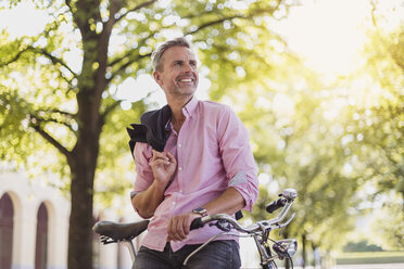 Lächelnder Mann mit Fahrrad in einem Park - DIGF02577