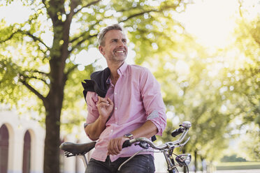 Smiling man with bicycle in a park - DIGF02577