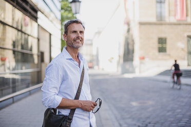 Smiling man looking around in the city - DIGF02580