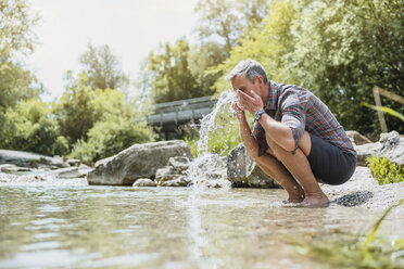 Wanderer macht eine Pause am Flussufer und wäscht sich das Gesicht - DIGF02608