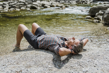 Hiker having a break at the riverbank - DIGF02609