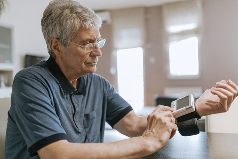 Älterer Mann misst seinen Blutdruck, lizenzfreies Stockfoto