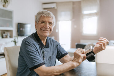 Smiling senior man taking his blood pressure - ZEDF00747