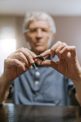 Senior man examining hearing aid - ZEDF00749